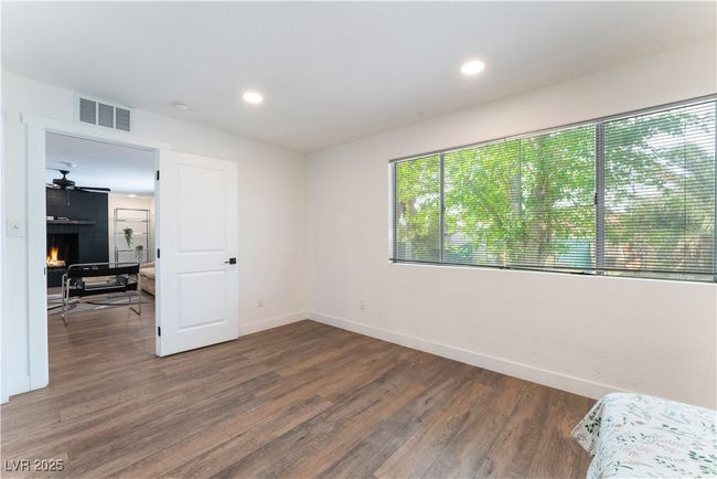 Bedroom featuring recessed lighting, baseboards, a large fireplace, visible vents, and wood finished floors | Image 20
