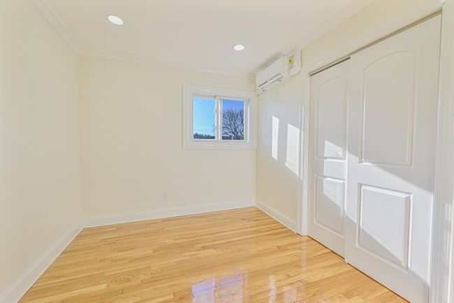 Spare room with ornamental molding, a wall mounted AC, and light wood-type flooring | Image 35