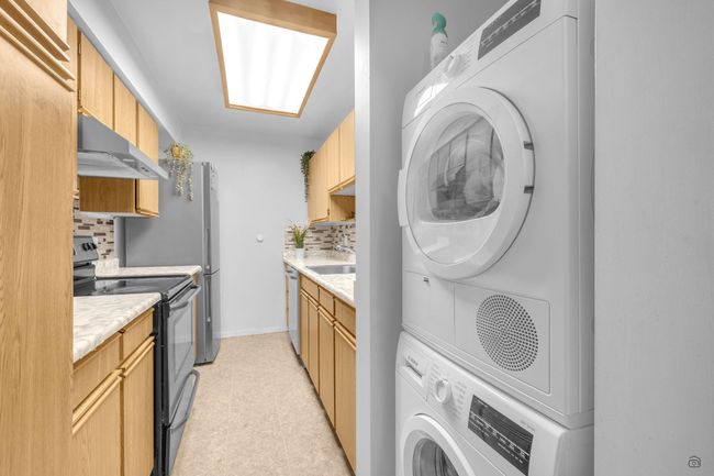 Clothes washing area with a sink, baseboards, stacked washer / dryer, and laundry area | Image 19