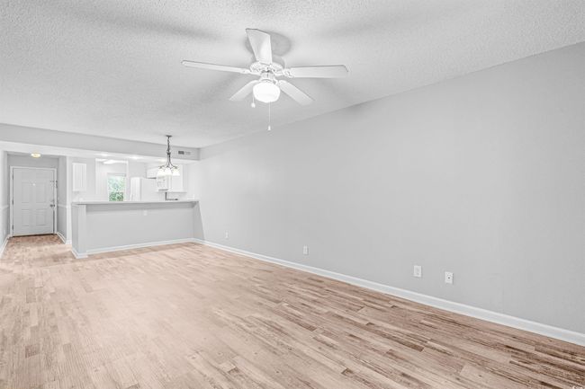Unfurnished living room with a textured ceiling, light wood-style floors, ceiling fan, and a chandelier | Image 14