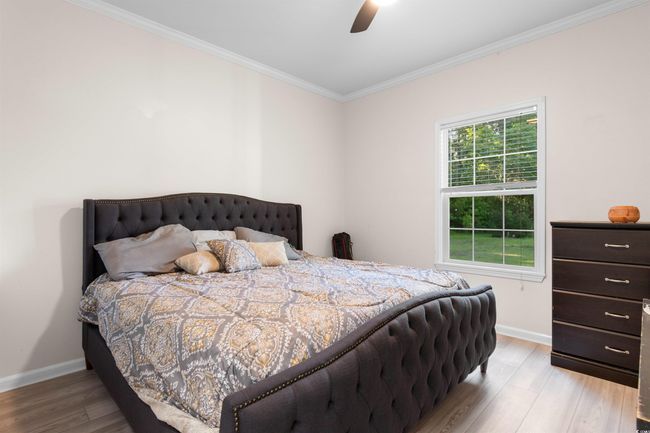 Bedroom with crown molding, baseboards, wood finished floors, and a ceiling fan | Image 14