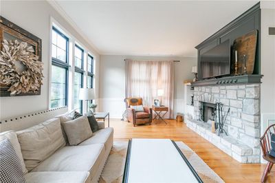 Living room featuring a stone fireplace, light wood-type flooring, and crown molding | Image 2