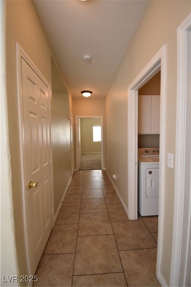 Hallway featuring baseboards, washer / dryer, and light tile patterned floors | Image 16