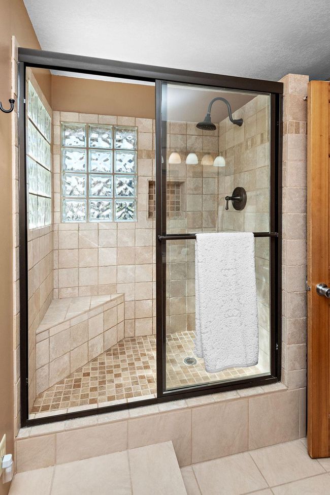 Newer tile shower with bench and natural light. | Image 21