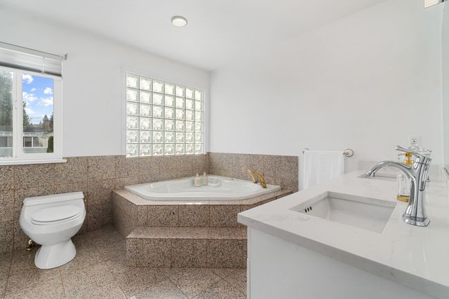 Full bathroom featuring tile walls, granite finish floor, toilet, vanity, and a bath | Image 23