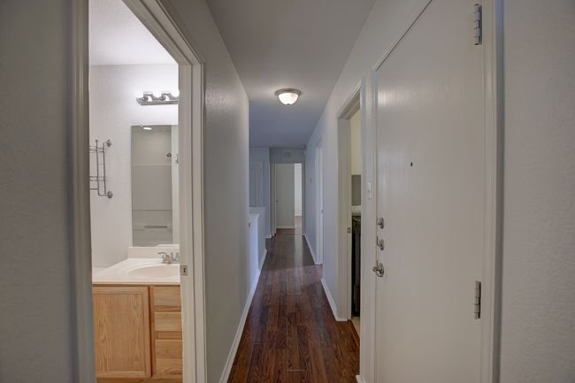 Hallway with dark wood-type flooring, a sink, and baseboards | Image 34