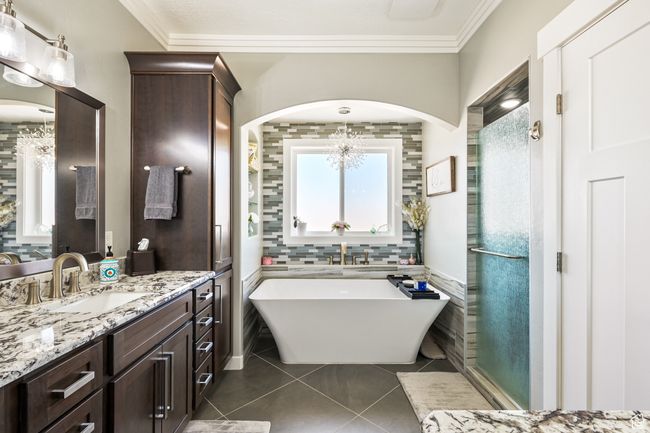 Full bath with tile patterned flooring, vanity, a chandelier, a freestanding bath, and healthy amount of natural light | Image 45