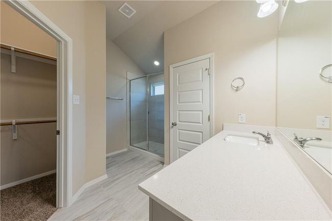Full bath with a spacious closet, vanity, a stall shower, lofted ceiling, and a ceiling fan | Image 11