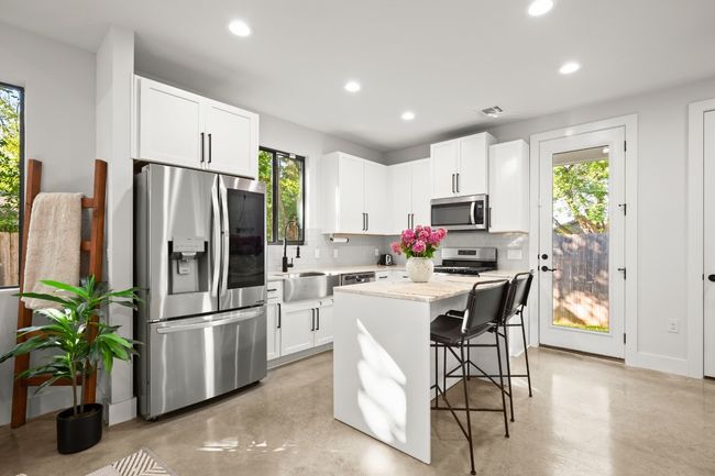 Kitchen featuring appliances with stainless steel finishes, backsplash, recessed lighting, a breakfast bar, and concrete floors | Image 11