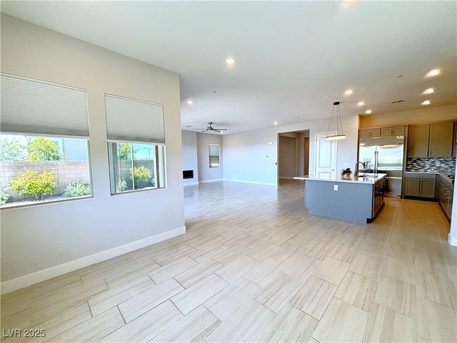 Kitchen with ceiling fan, a center island with sink, built in fridge, baseboards, and open floor plan | Image 9