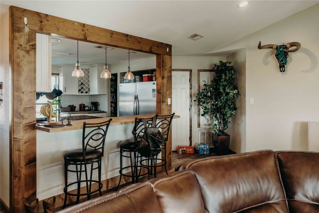 Kitchen featuring freestanding refrigerator, recessed lighting, a kitchen bar, tasteful backsplash, and hanging light fixtures | Image 8