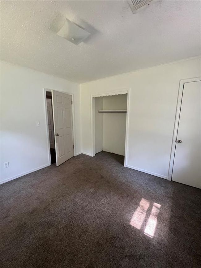 Unfurnished bedroom featuring dark carpet, a textured ceiling, and baseboards | Image 12