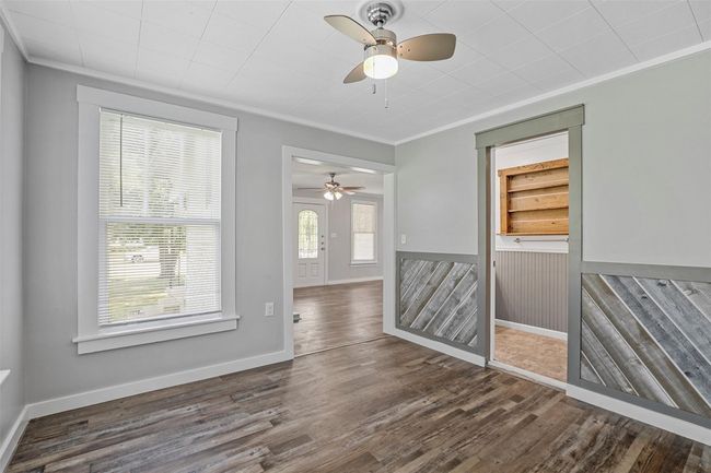 Empty room with a ceiling fan, crown molding, and wood finished floors | Image 12