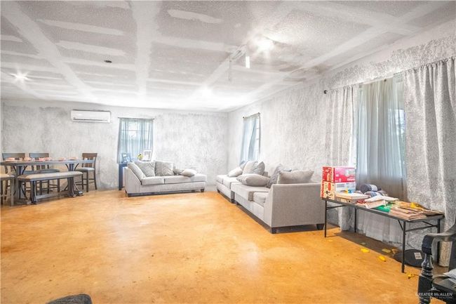 Living room featuring finished concrete floors, a wall mounted air conditioner, and a textured ceiling | Image 7