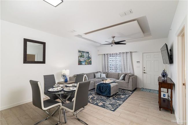 Dining space with a tray ceiling, visible vents, ceiling fan, and light wood finished floors | Image 4
