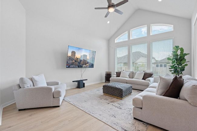 Living area featuring recessed lighting, light wood-type flooring, baseboards, high vaulted ceiling, and ceiling fan | Image 7