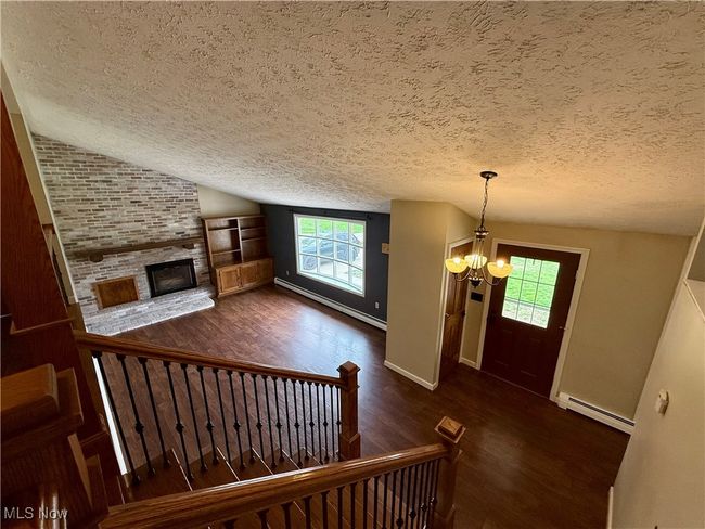 Foyer featuring a textured ceiling, baseboard heating, wood finished floors, and a chandelier | Image 34