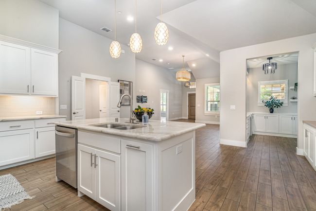Kitchen with a sink, stainless steel dishwasher, wood finished floors, white cabinetry, and high vaulted ceiling | Image 13