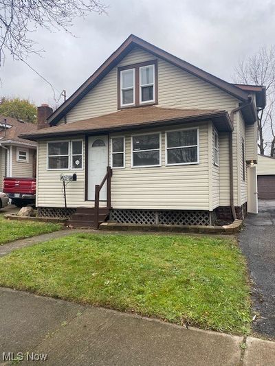 View of front of home with a front yard, a garage, and an outdoor structure | Image 1