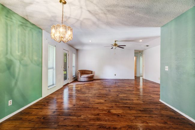 Empty room with wood finished floors, a chandelier, ceiling fan, and a textured ceiling | Image 6