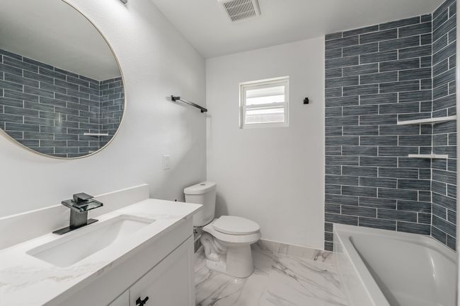 Bathroom with vanity, marble look tile flooring, toilet, shower / bath combination, and baseboards | Image 4