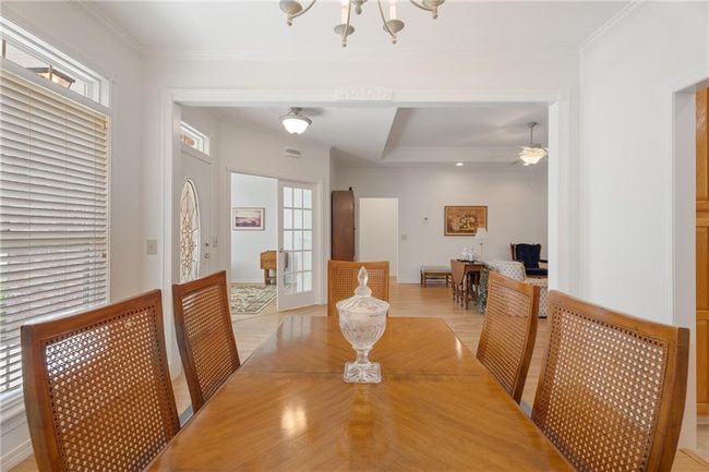 Dining area featuring plenty of natural light, light wood finished floors, ceiling fan with notable chandelier, and ornamental molding | Image 11