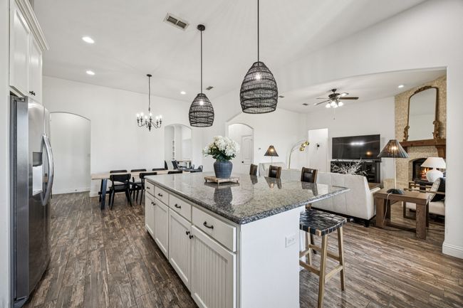 Kitchen featuring stainless steel refrigerator with ice dispenser, arched walkways, recessed lighting, and dark wood-style flooring | Image 7