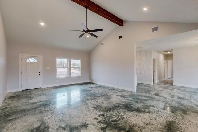 Unfurnished living room with concrete flooring, beam ceiling, a ceiling fan, and visible vents | Image 4