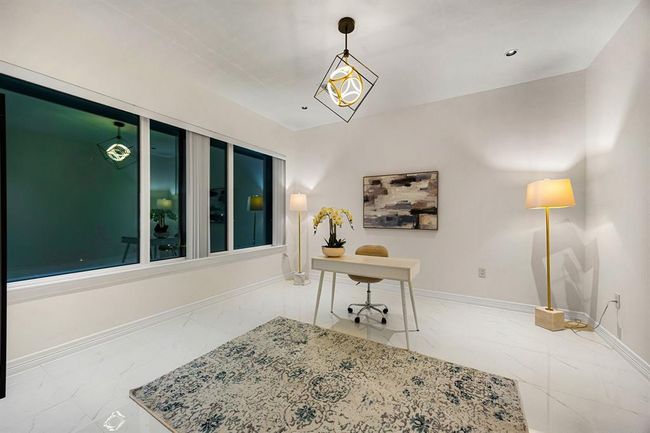This sleek and sophisticated home office offers the perfect blend of style and functionality. Featuring glossy marble-look tile floors, contemporary lighting, and expansive windows that invite in natural light, the space is ideal for productivity in a serene, upscale setting. | Image 19