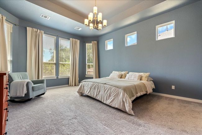 Carpeted bedroom featuring baseboards, visible vents, multiple windows, and an inviting chandelier | Image 17