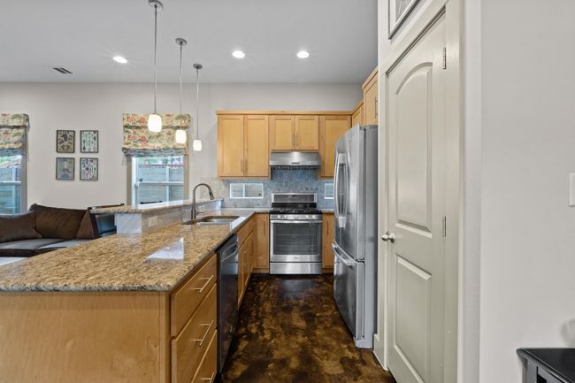 Kitchen with tasteful backsplash, a sink, a peninsula, under cabinet range hood, and stainless steel appliances | Image 7