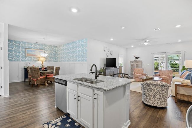 Kitchen featuring open floor plan, stainless steel dishwasher, wallpapered walls, a sink, and wainscoting | Image 8