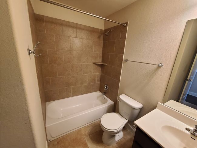 Full bath with shower combination, vanity, a textured wall, and tile patterned floors | Image 31