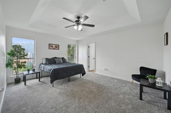 Bedroom with a raised ceiling, carpet floors, baseboards, and ceiling fan | Image 13