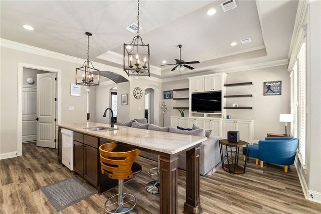 The sink is thoughtfully placed on the island with the breakfast bar, making it easy to chat with guests or family while preparing meals or cleaning up. This view also offers a clear look at the home’s open layout. | Image 13