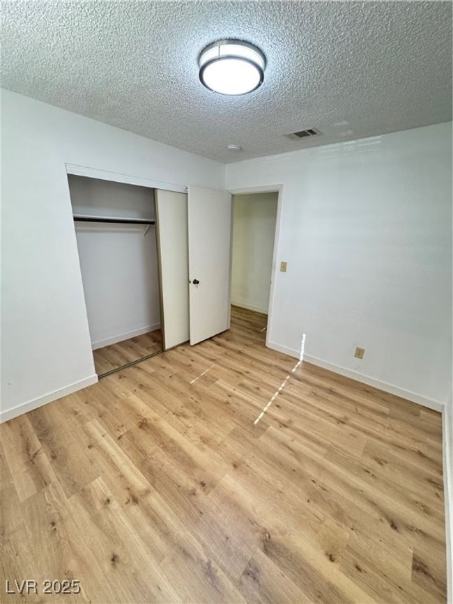 Unfurnished bedroom with wood finished floors, a closet, and a textured ceiling | Image 38
