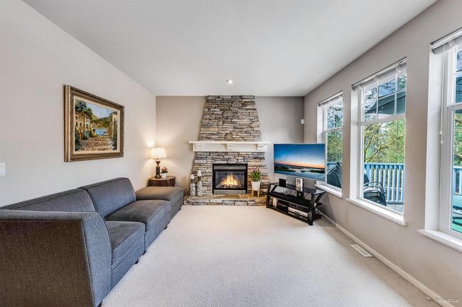 Carpeted living area featuring visible vents, baseboards, and a stone fireplace | Image 10