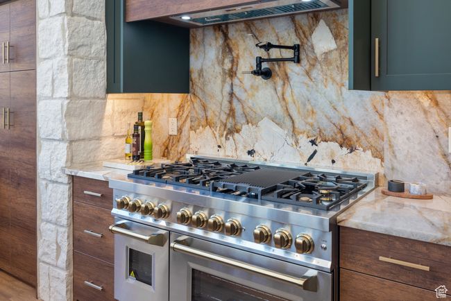 Kitchen with double oven range, backsplash, extractor fan, and light stone countertops | Image 32