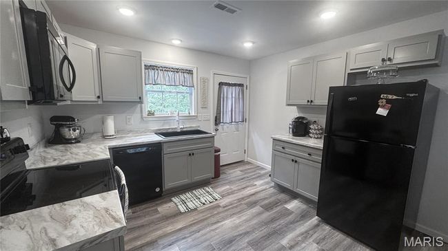 Kitchen with black appliances, a sink, gray cabinetry, light wood finished floors, and baseboards | Image 4