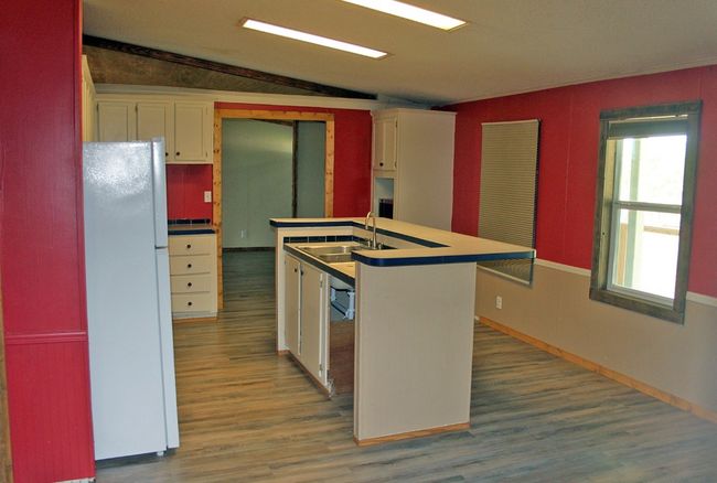 Kitchen with freestanding refrigerator, a sink, vaulted ceiling, wood finished floors, and white cabinets | Image 18
