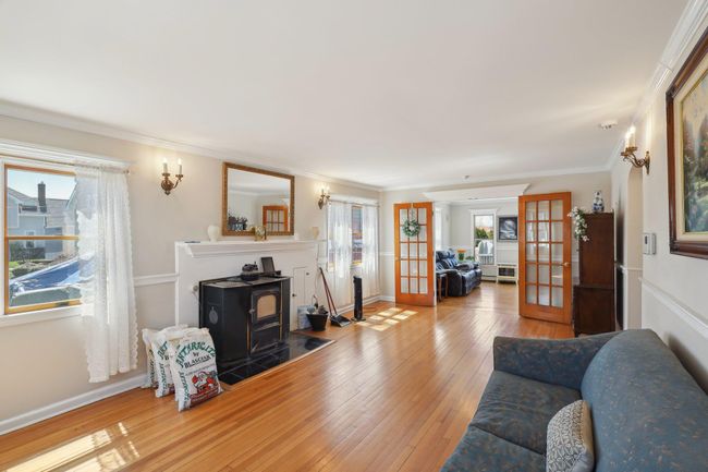 Living area with ornamental molding, wood-type flooring, a wood stove, and french doors | Image 7