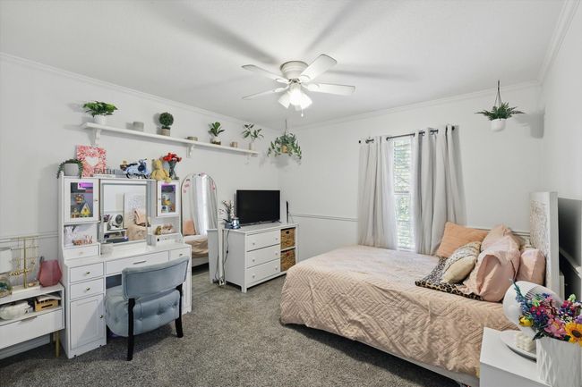Carpeted bedroom featuring crown molding, ceiling fan, and an office area | Image 26