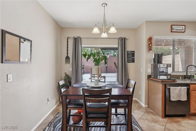 Dining room featuring a chandelier, light tile patterned floors, baseboards, and a textured wall | Image 21