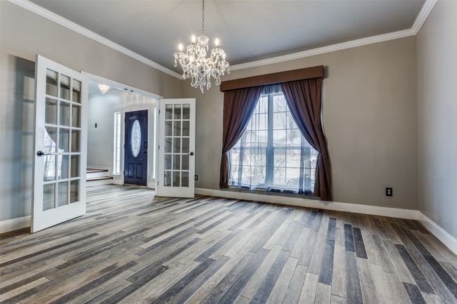 Spare room with french doors, baseboards, wood finished floors, and a chandelier | Image 4