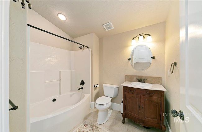 Bathroom with vanity, tub / shower combination, a textured ceiling, tile patterned flooring, and a textured wall | Image 34