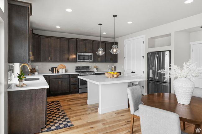 Kitchen featuring dark brown cabinetry, recessed lighting, stainless steel appliances, a sink, and light wood-type flooring | Image 14