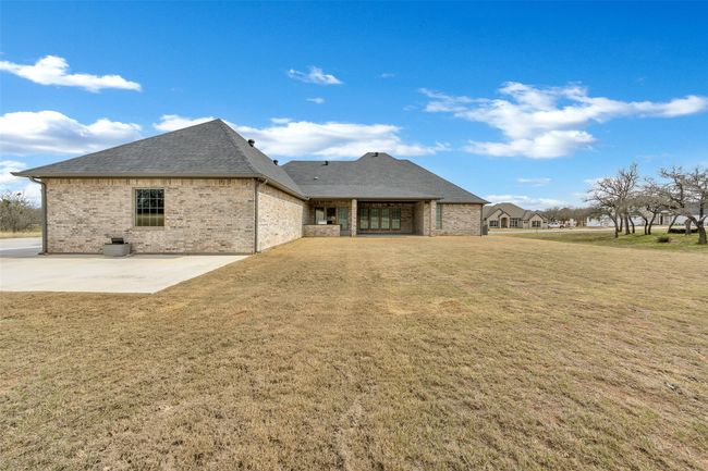 Back of property featuring a patio area, brick siding, a yard, and roof with shingles | Image 39