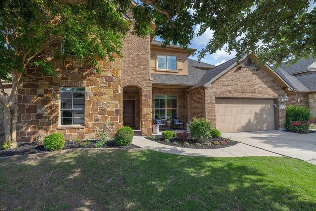 Traditional-style home featuring driveway, a garage, brick siding, a front lawn, and a shingled roof | Image 14