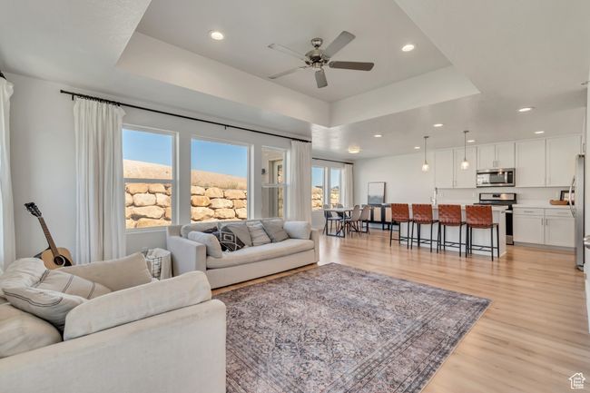 Living room featuring plenty of natural light, a raised ceiling, light wood finished floors, ceiling fan, and recessed lighting | Image 11