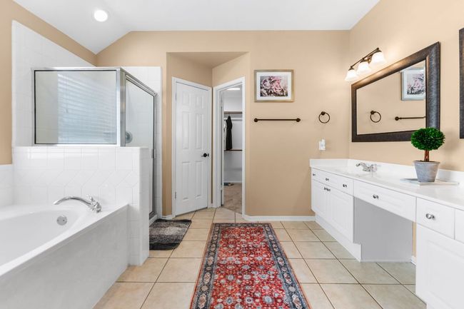 Bathroom featuring vanity, a stall shower, a garden tub, tile patterned floors, and lofted ceiling | Image 20